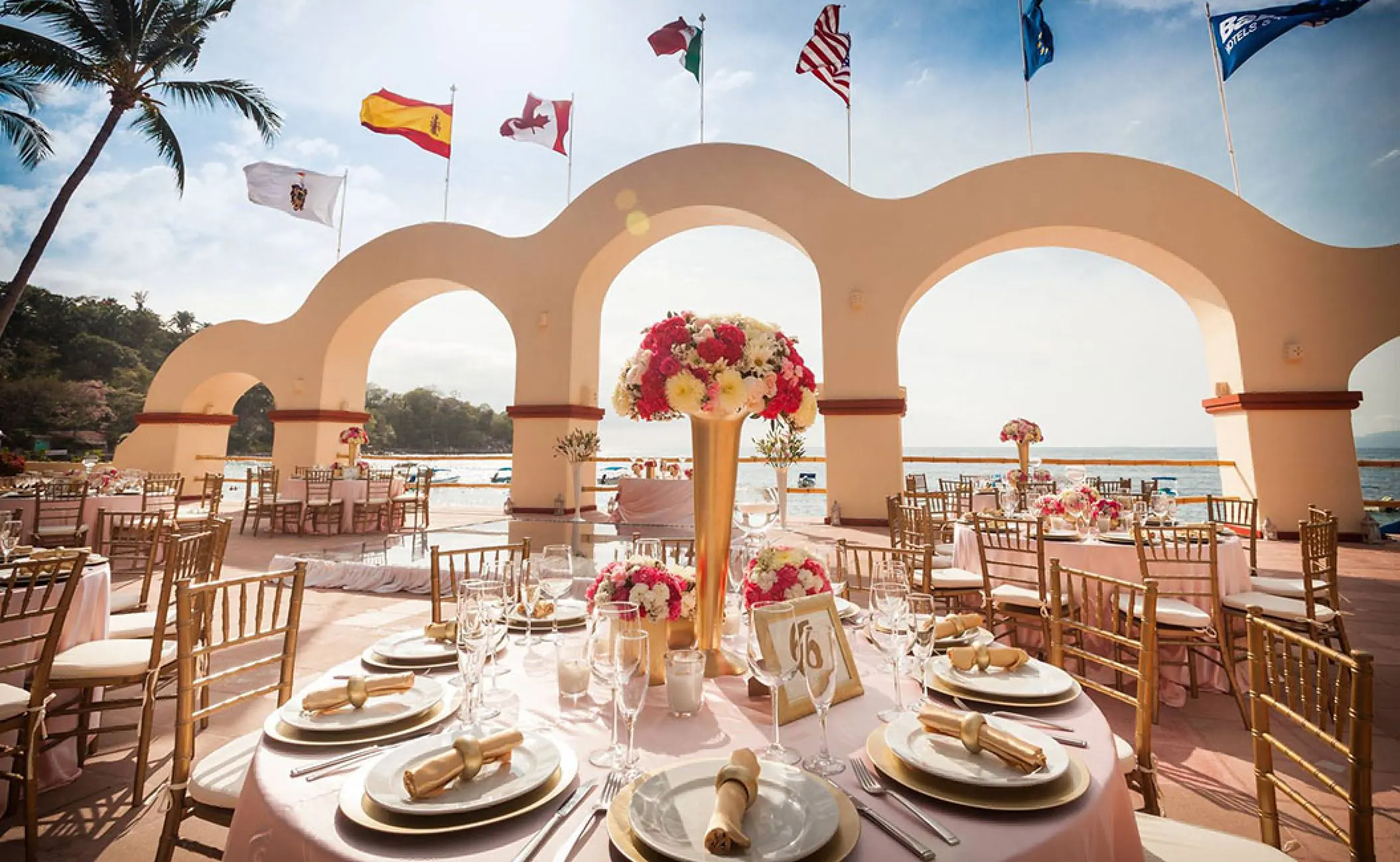 Terrace wedding reception with arched columns and floral centerpieces at Barcelo Puerto Vallarta, Puerto Vallarta