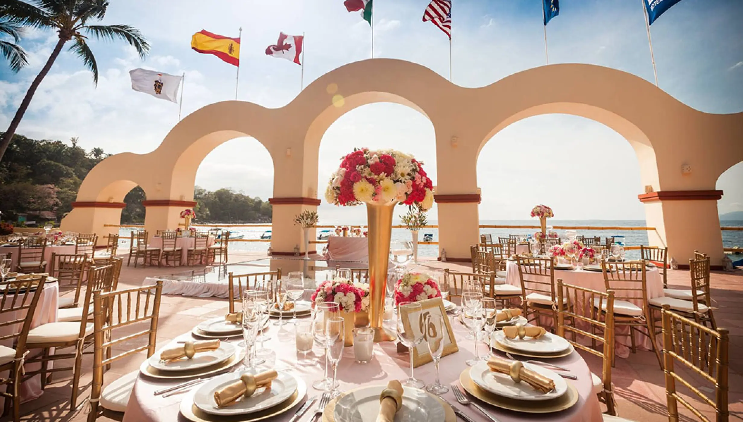Terrace wedding reception with arched columns and floral centerpieces at Barcelo Puerto Vallarta, Puerto Vallarta