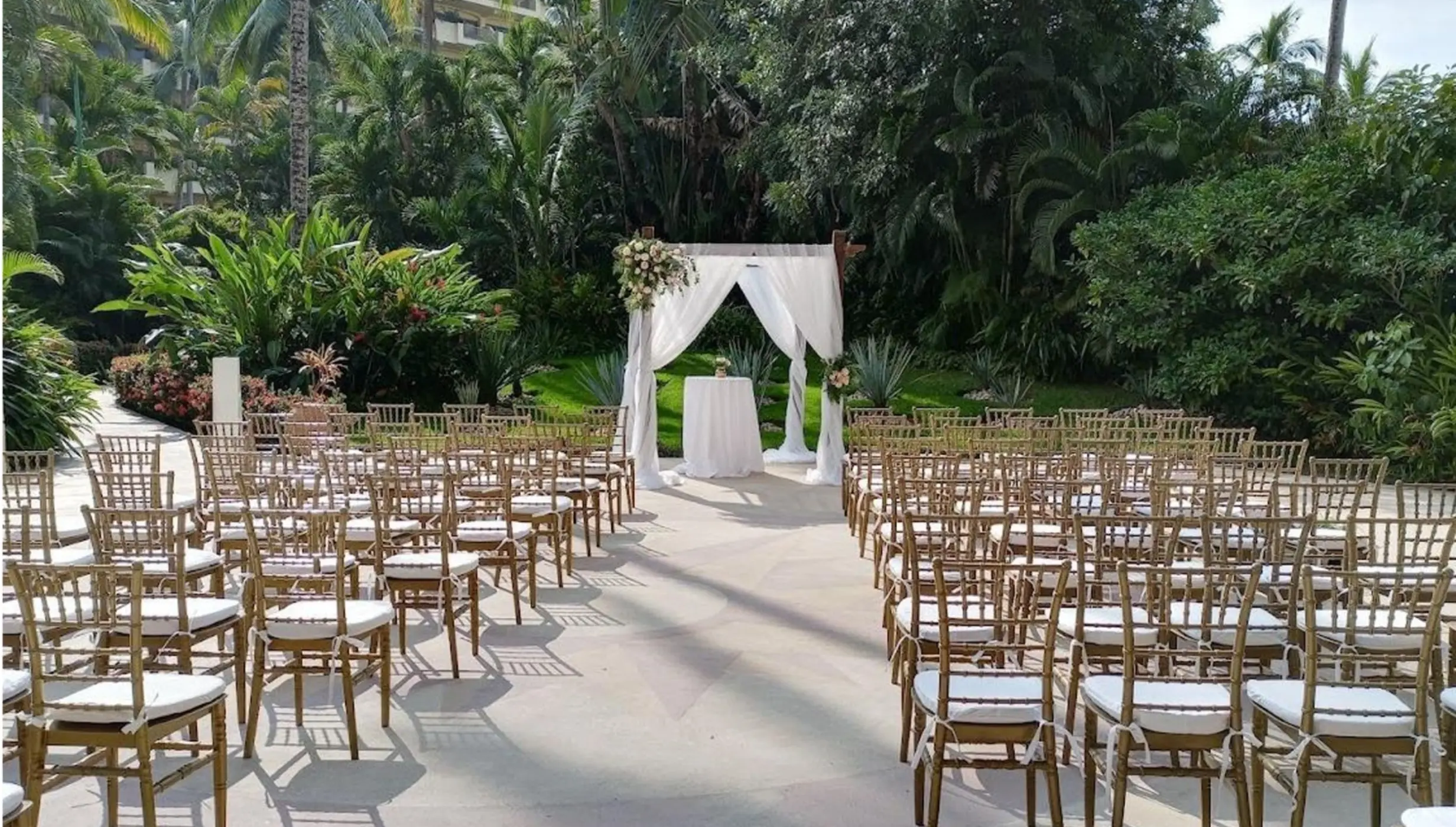 La Placita wedding ceremony with gold chairs and a white draped arch at Barcelo Puerto Vallarta