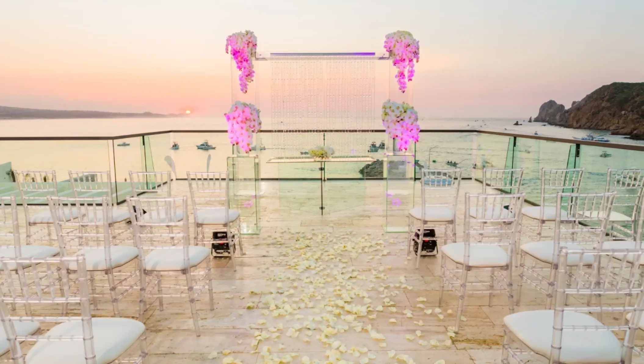 Rooftop wedding ceremony with purple floral arch and clear chairs at Breathless Cabo San Lucas, Cabo San Lucas