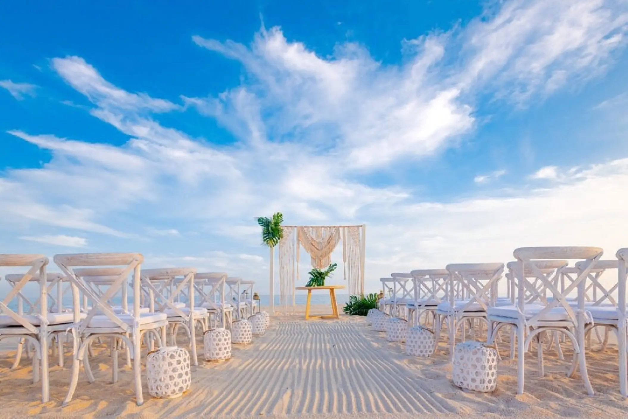 Beachfront wedding ceremony setup with white cross-back chairs at Zoetry Casa del Mar, Los Cabos