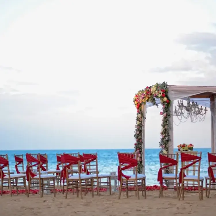 Beachfront wedding ceremony with red sashes at Breathless Punta Cana, Punta Cana