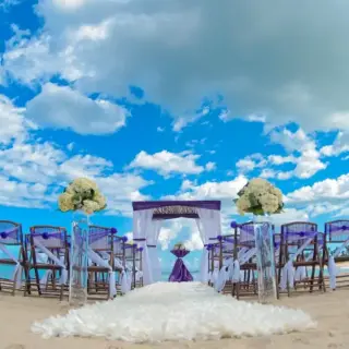 Beachfront wedding ceremony setup with purple accents and white floral aisle at Breathless Punta Cana, Punta Cana