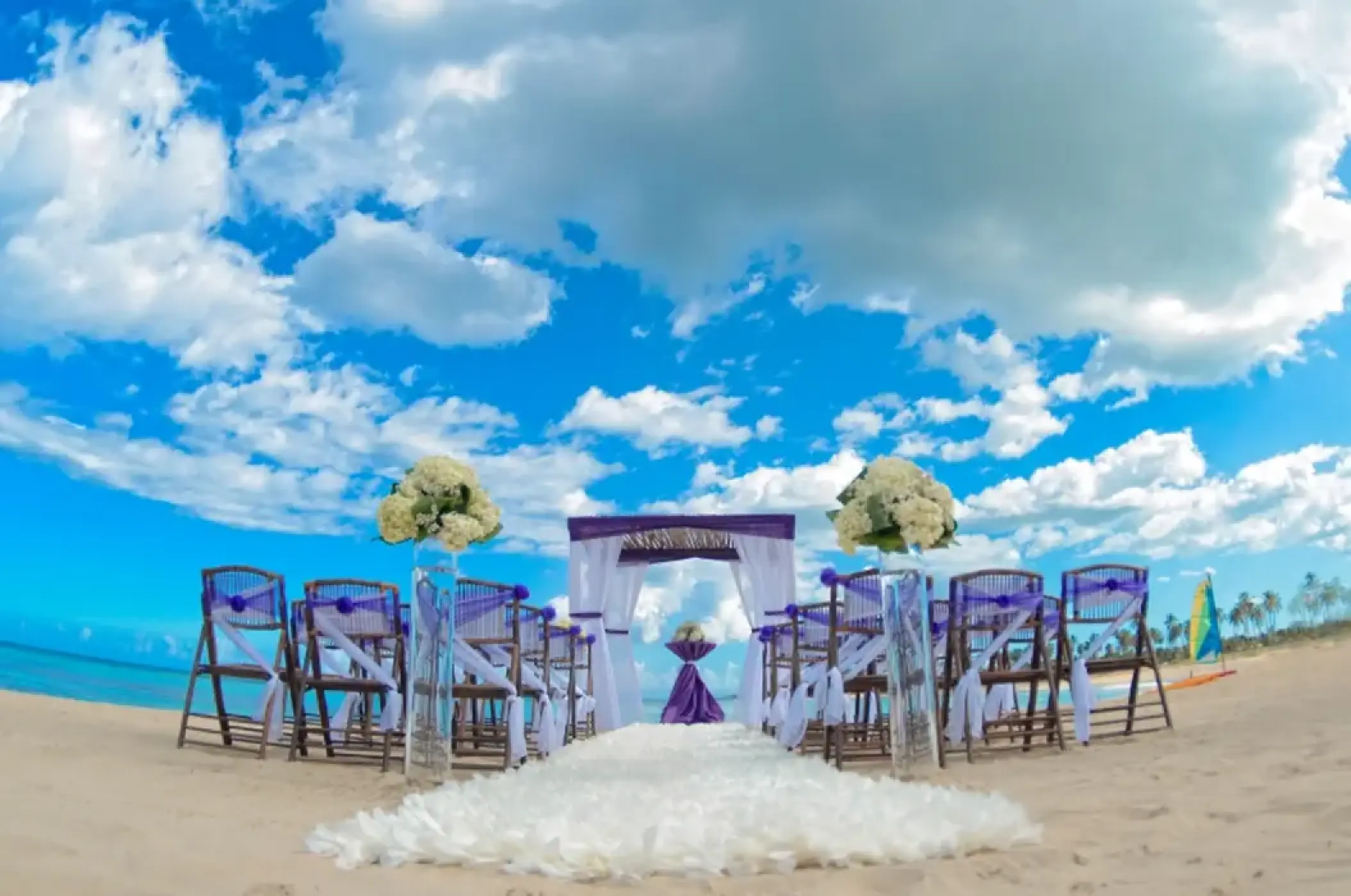 Beachfront wedding ceremony setup with purple accents and white floral aisle at Breathless Punta Cana, Punta Cana