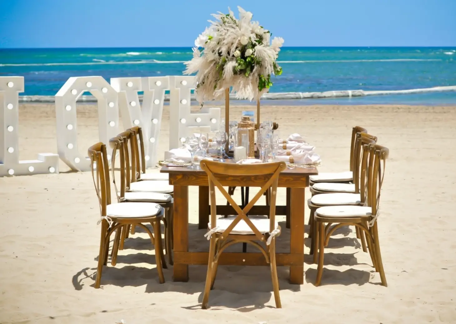 Beachfront wedding reception at Breathless Punta Cana with wooden table and marquee LOVE letters, Punta Cana