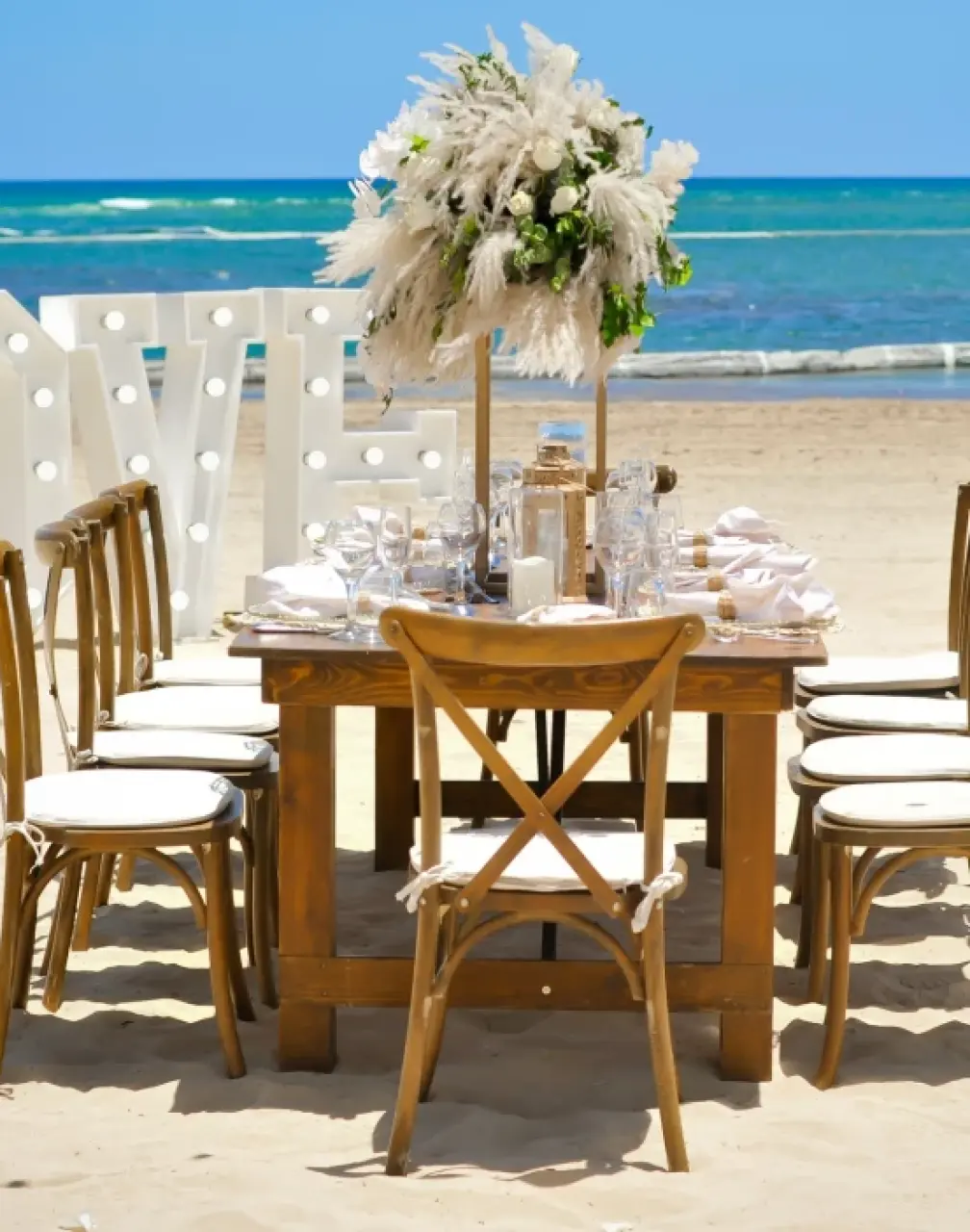 Beachfront wedding reception at Breathless Punta Cana with wooden table and marquee LOVE letters, Punta Cana