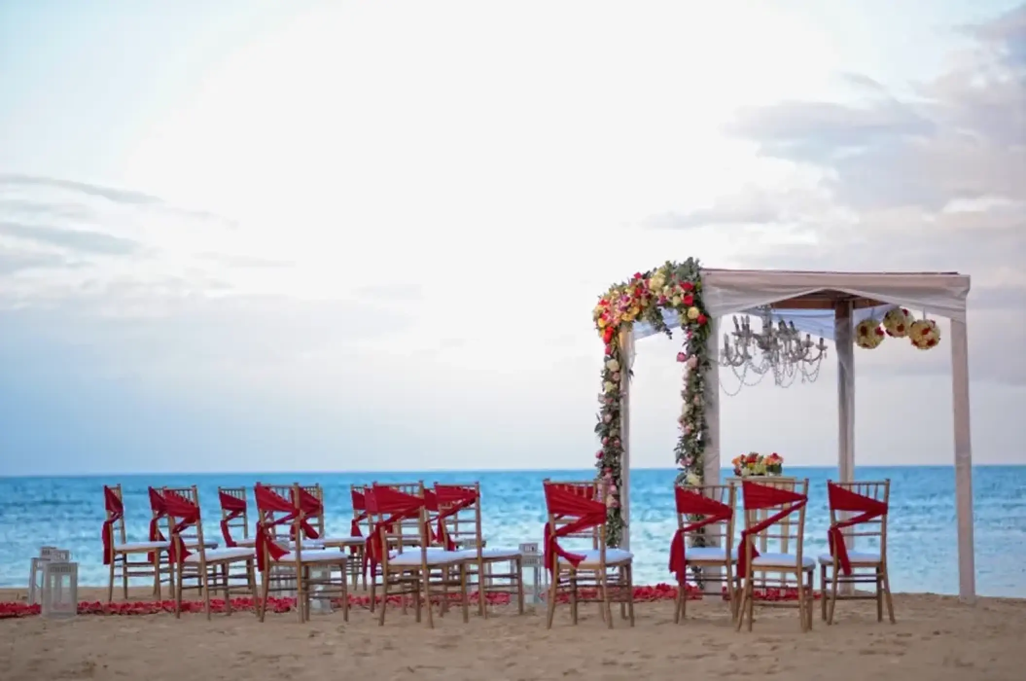 Beachfront wedding ceremony with red sashes and floral gazebo at Breathless Punta Cana