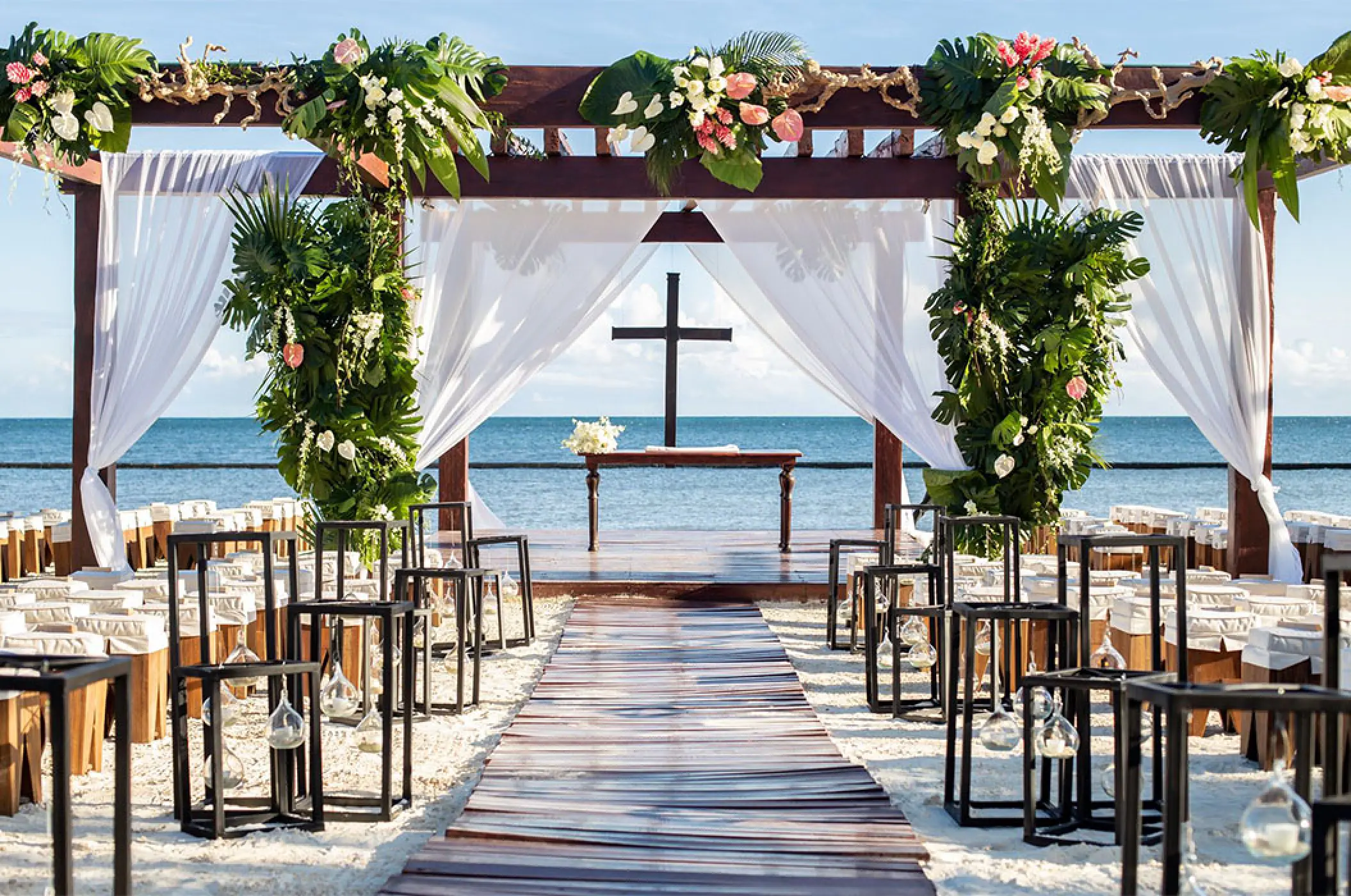 Beachfront wedding ceremony with a cross and floral gazebo at Breathless Riviera Cancun, Riviera Maya