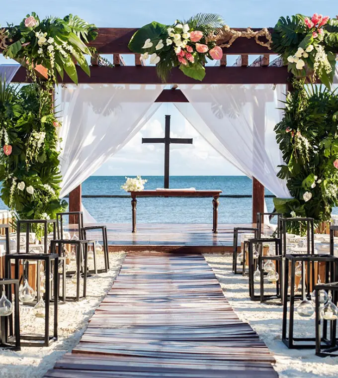 Beachfront wedding ceremony with a cross and floral gazebo at Breathless Riviera Cancun, Riviera Maya