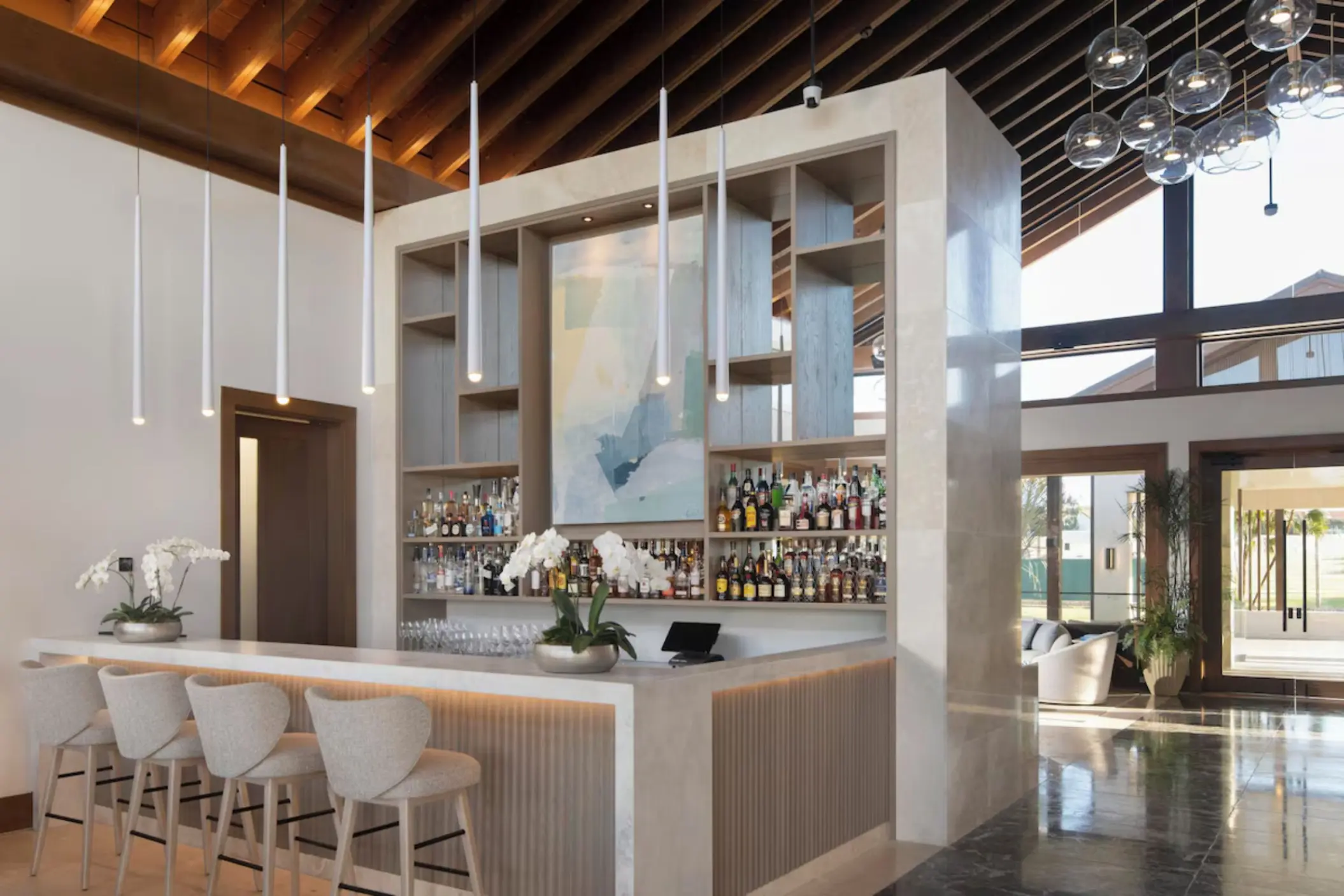 Modern indoor bar with white barstools and slatted wood ceiling at Casa de Campo, La Romana