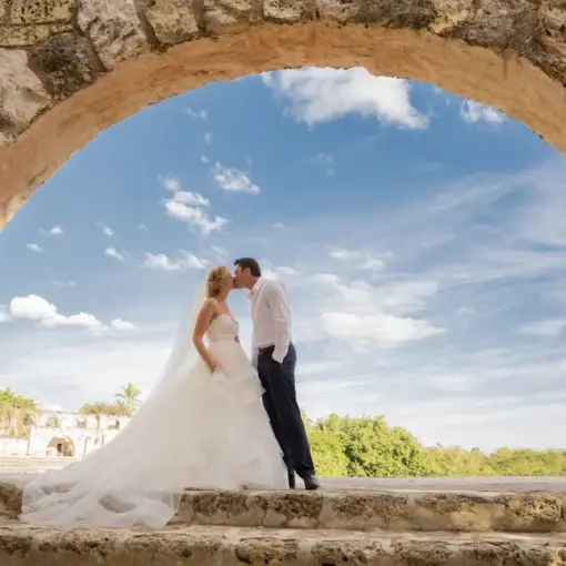 Bride and groom kissing under a stone arch at Casa de Campo, La Romana