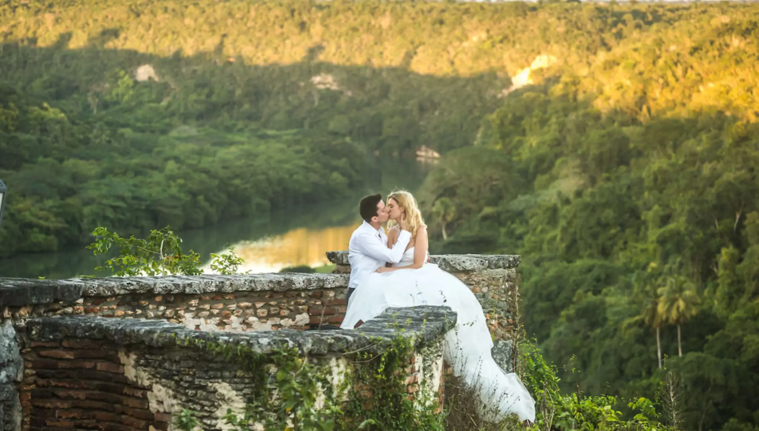 Bride and groom kissing on a stone terrace overlooking the Chavón River at Casa de Campo, La Romana