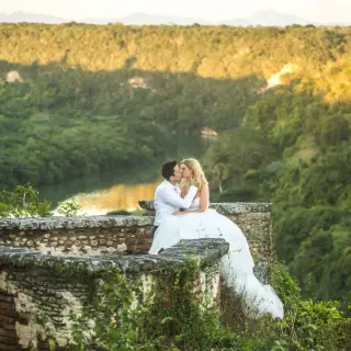 Bride and groom kissing on a stone terrace overlooking the Chavón River at Casa de Campo, La Romana