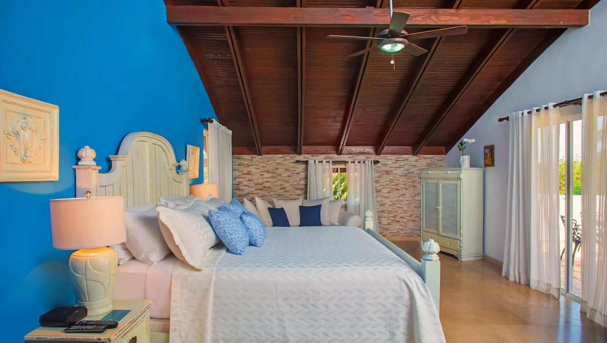 Guest suite with a blue accent wall and wood-beamed ceiling at Casa de Campo, La Romana