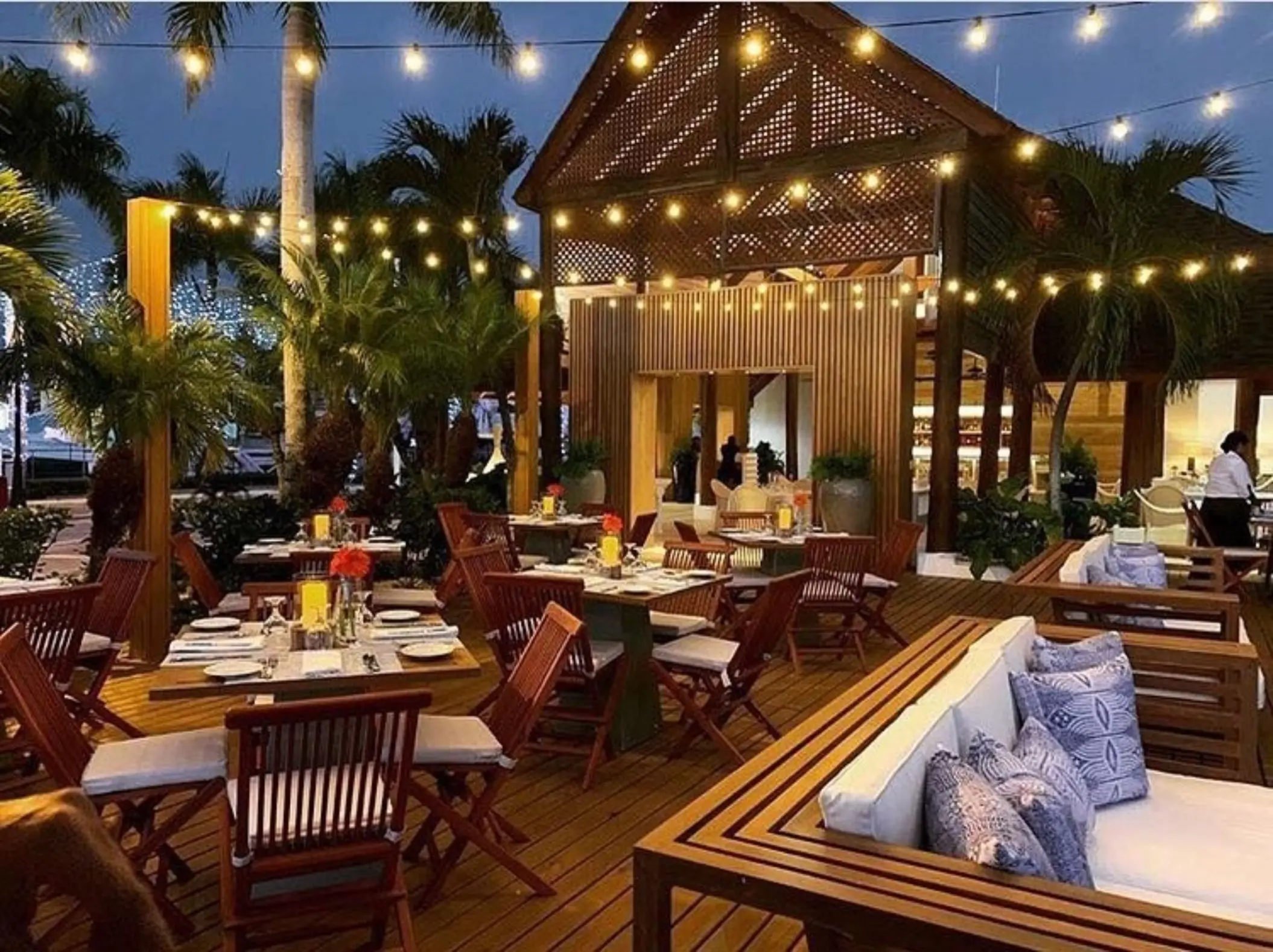 Outdoor wedding reception venue at Casa de Campo with string lights and wooden tables, La Romana