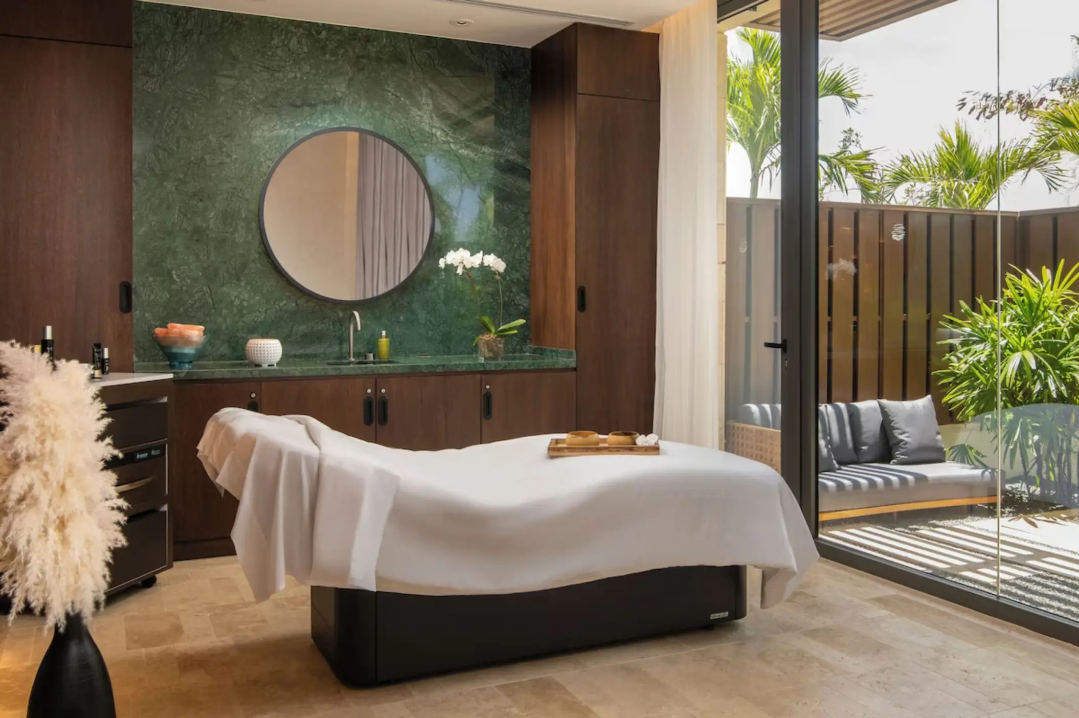 Spa massage treatment room with a white bed and outdoor patio at Casa de Campo, La Romana