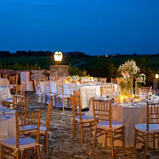 Evening wedding reception terrace with round tables and lit lanterns at Casa de Campo, La Romana