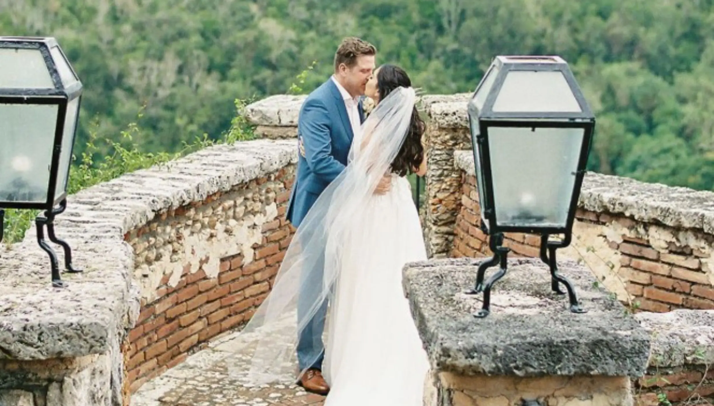 Bride and groom kissing on a stone terrace at Casa de Campo, La Romana