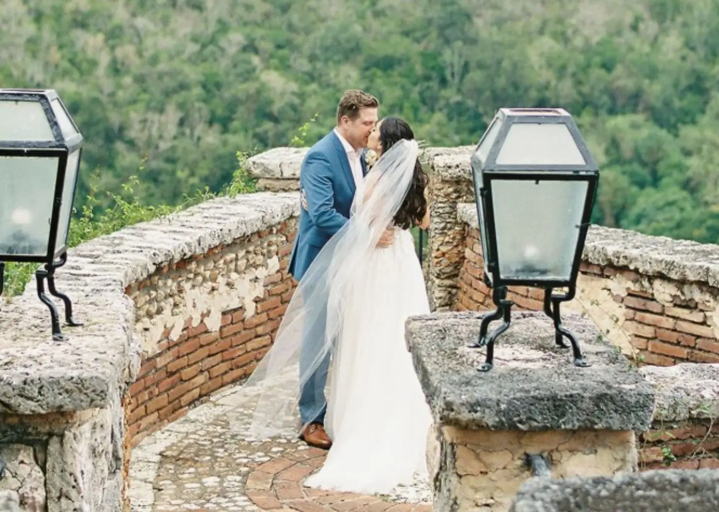 Bride and groom kissing on a stone terrace at Casa de Campo, La Romana