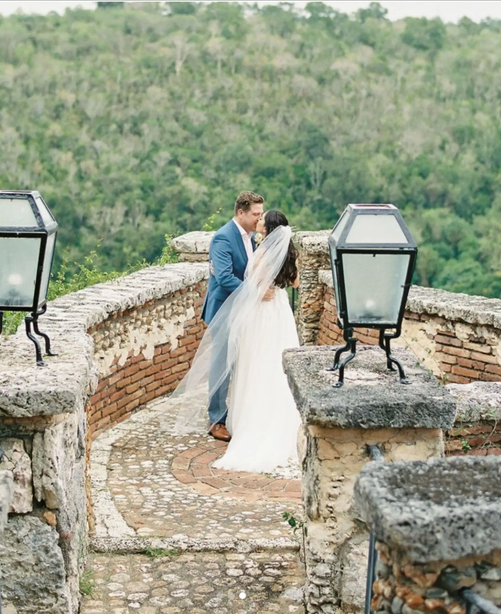 Bride and groom kissing on a stone terrace at Casa de Campo, La Romana