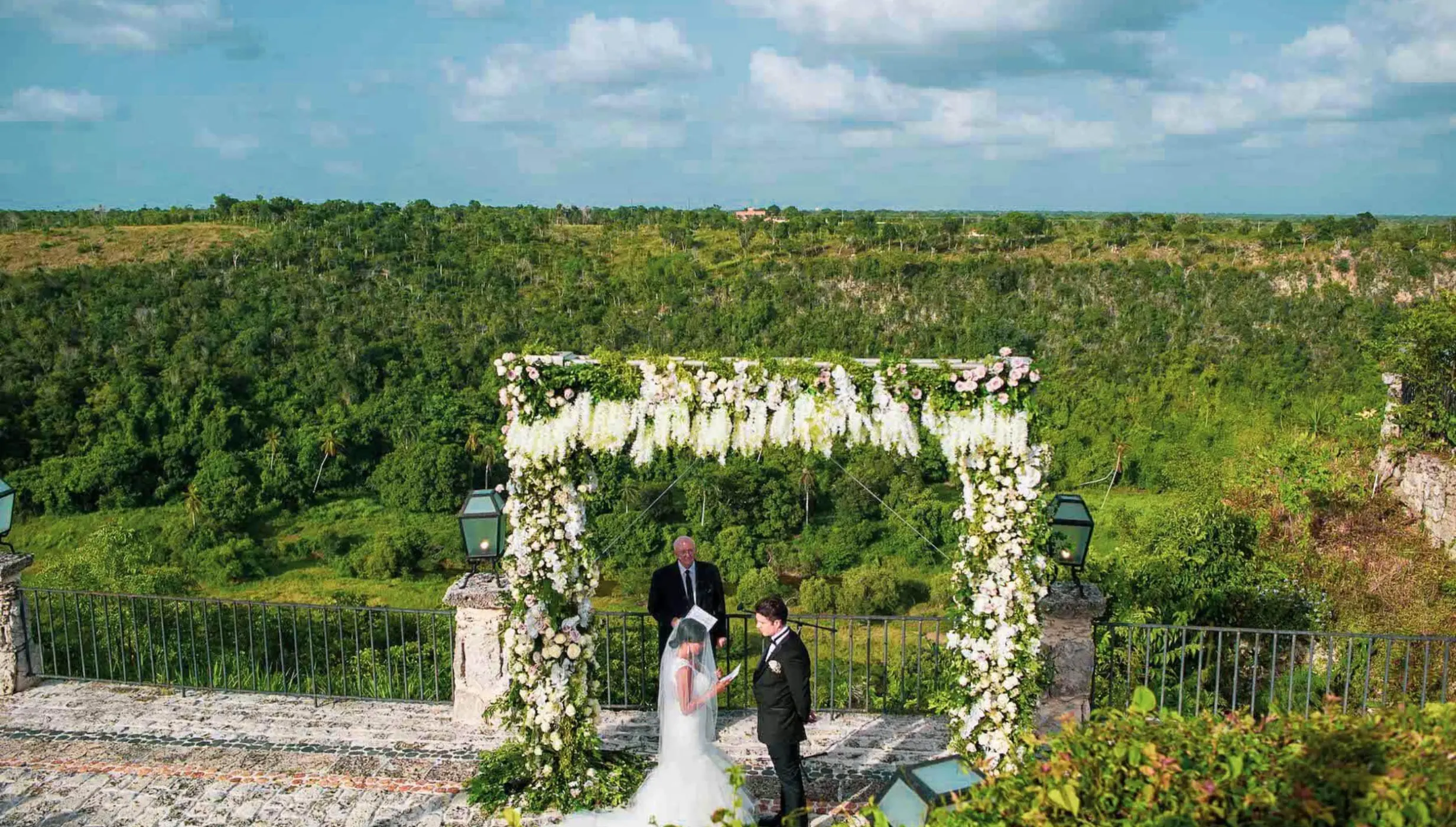 Outdoor wedding ceremony under a floral arch at Casa de Campo, La Romana