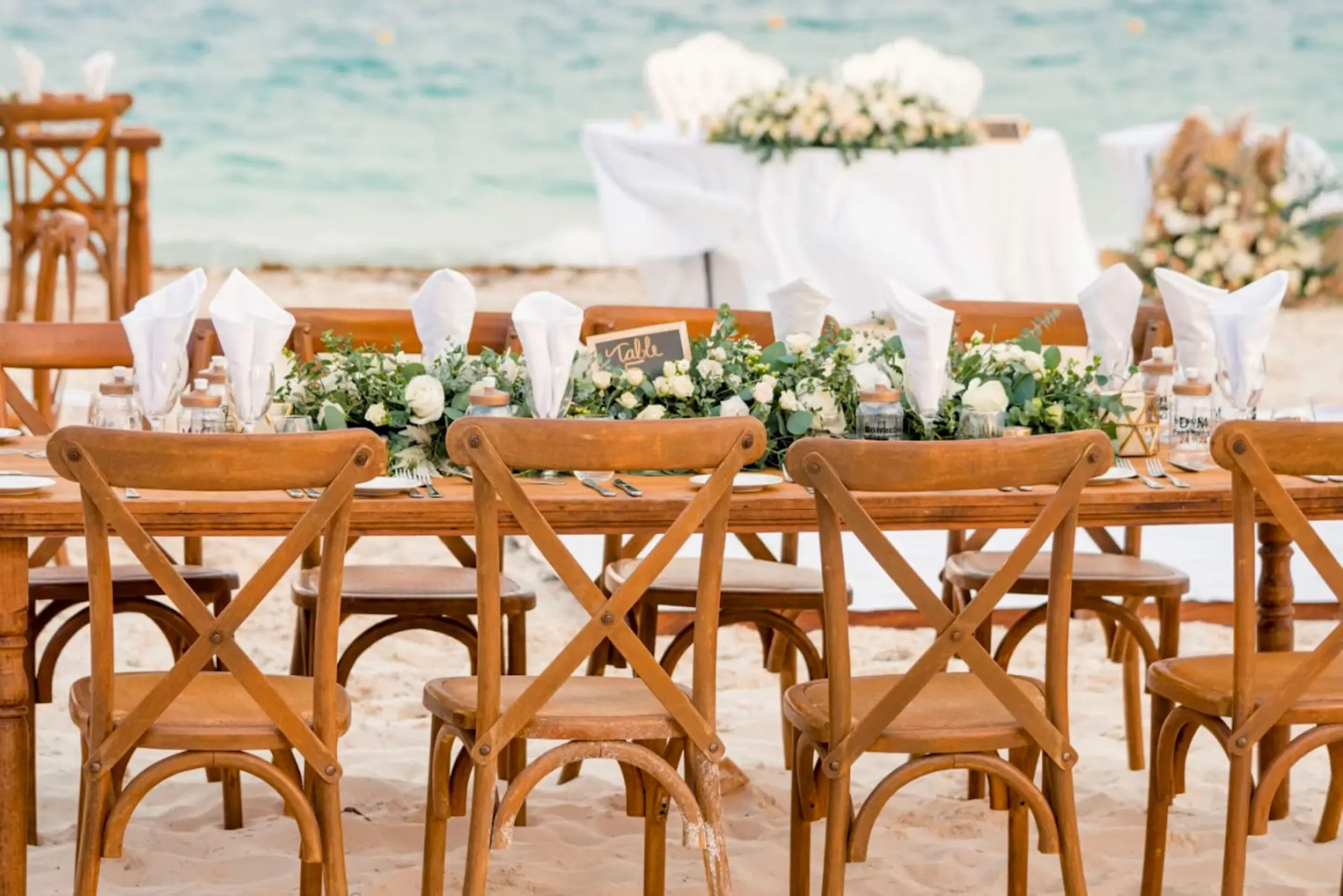 Beach wedding reception with wooden cross-back chairs at Catalonia Grand Costa Mujeres, Cancun