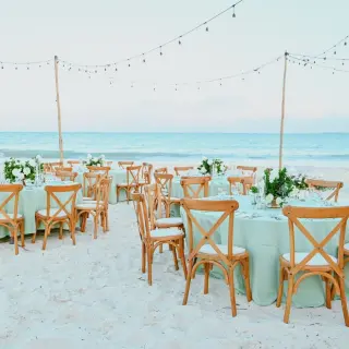 Beachfront wedding reception with round tables and string lights at Catalonia Grand Costa Mujeres, Cancun