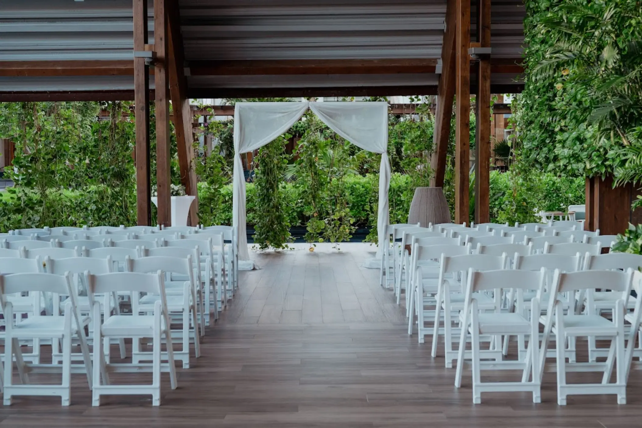 Wedding ceremony setup with white chairs and fabric arch under a wooden pavilion at Catalonia Grand Costa Mujeres, Cancun