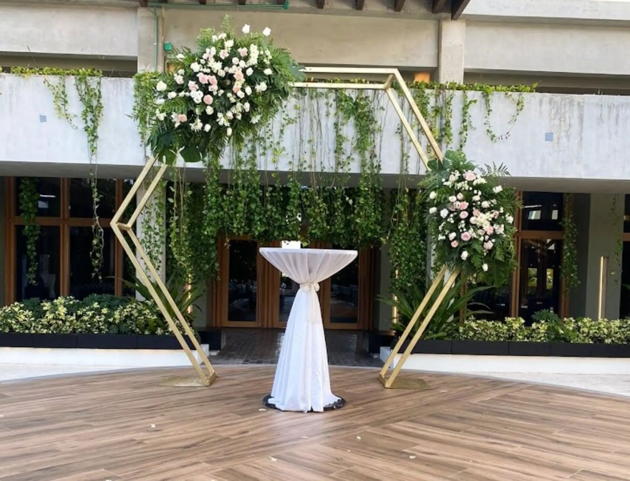 Hexagonal gold wedding arch with white flowers and greenery at Catalonia Grand Costa Mujeres, Cancun