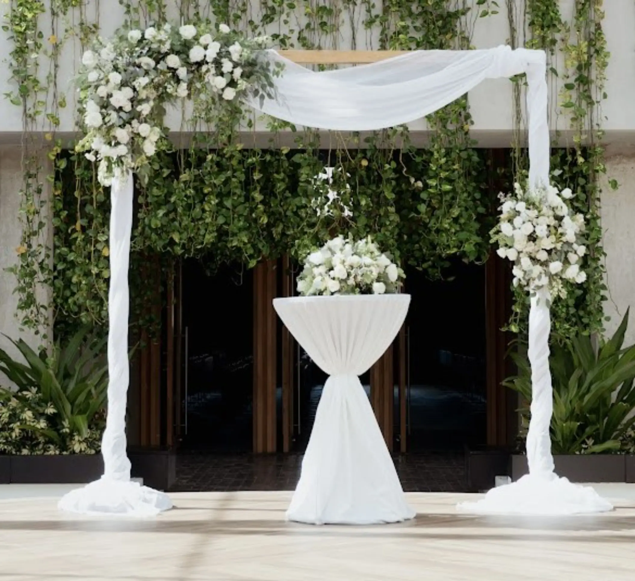 White fabric draped wedding arch with floral arrangements at Catalonia Grand Costa Mujeres, Cancun