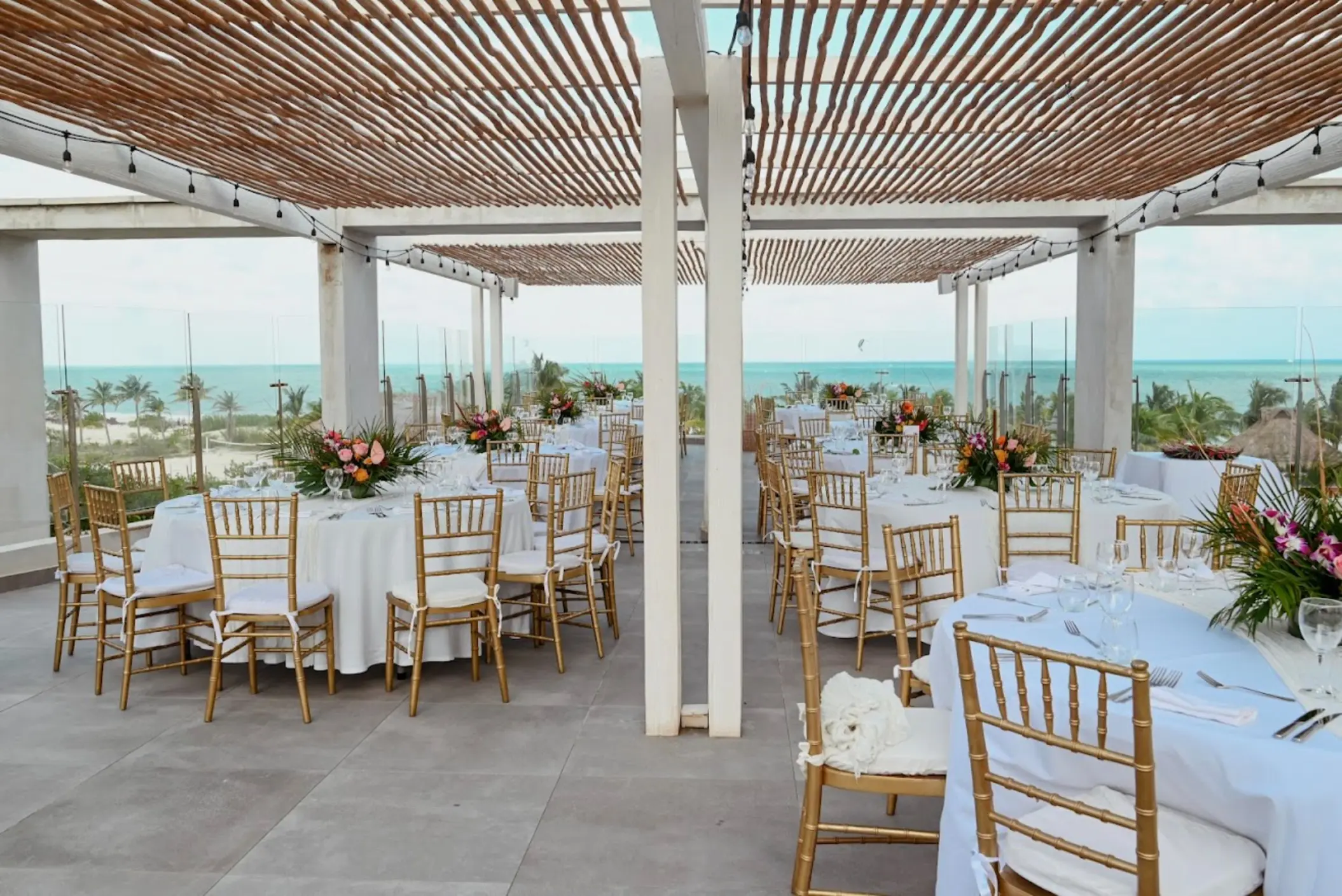 Terrace wedding reception with gold chairs under a wooden pergola at Catalonia Grand Costa Mujeres, Cancun
