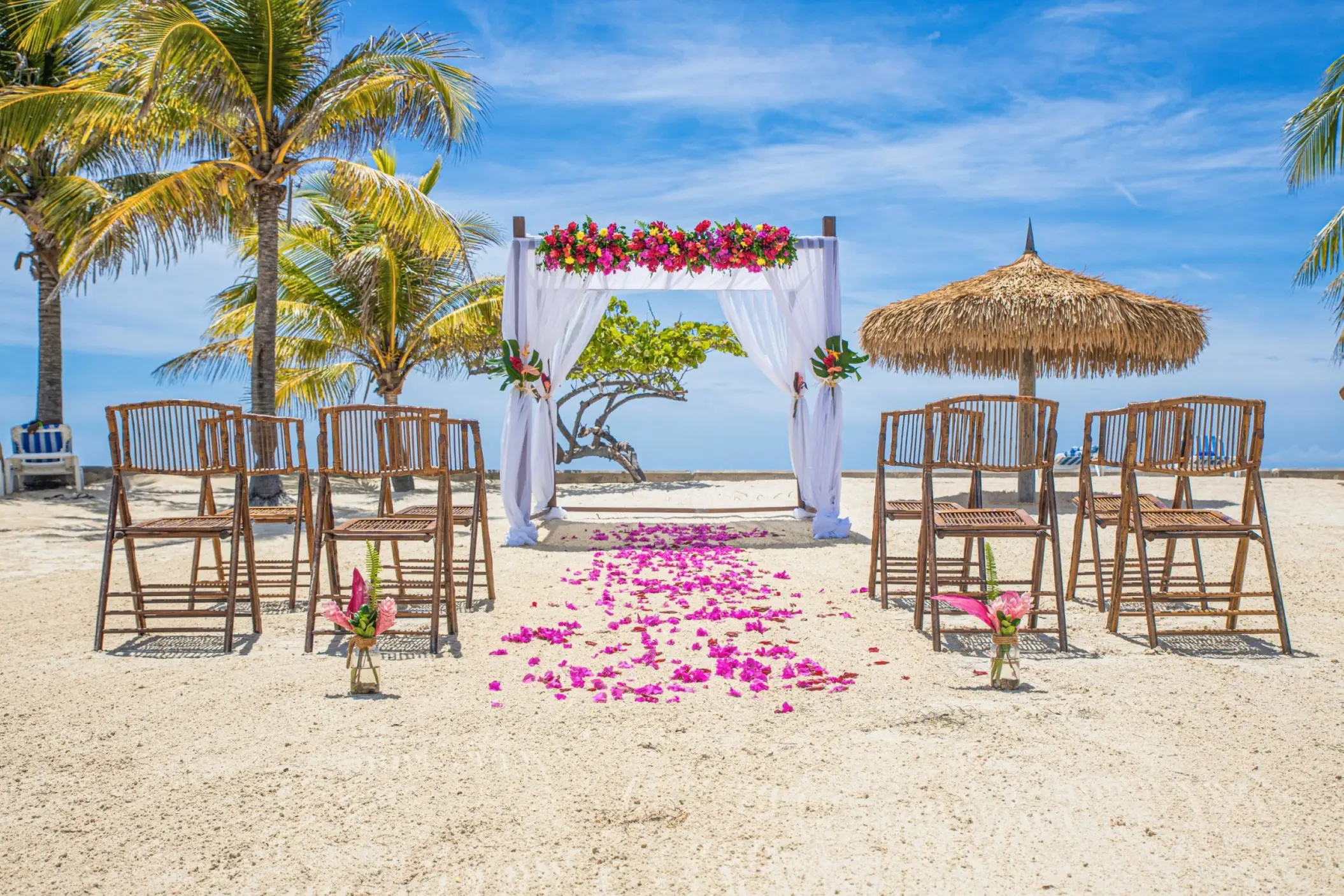 Beachfront wedding ceremony with a floral arch and bamboo chairs at Catalonia Montego Bay