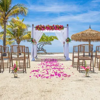 Beachfront wedding ceremony with a floral arch and bamboo chairs at Catalonia Montego Bay