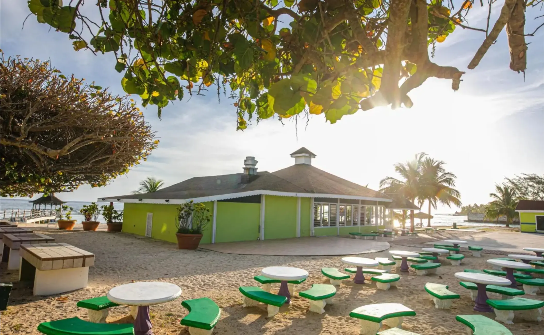 Outdoor picnic area with green tables and benches at Catalonia Montego Bay