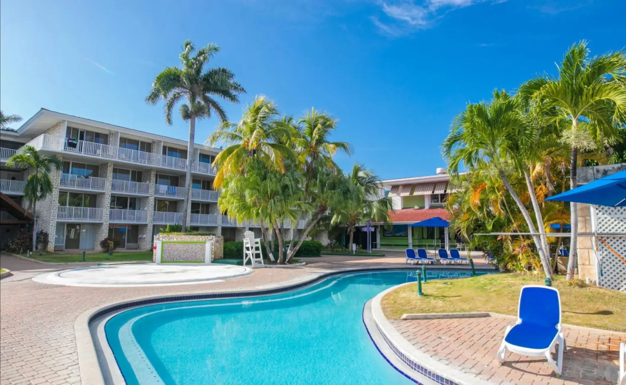 Curved swimming pool surrounded by palm trees and guest room buildings at Catalonia Montego Bay, Montego Bay