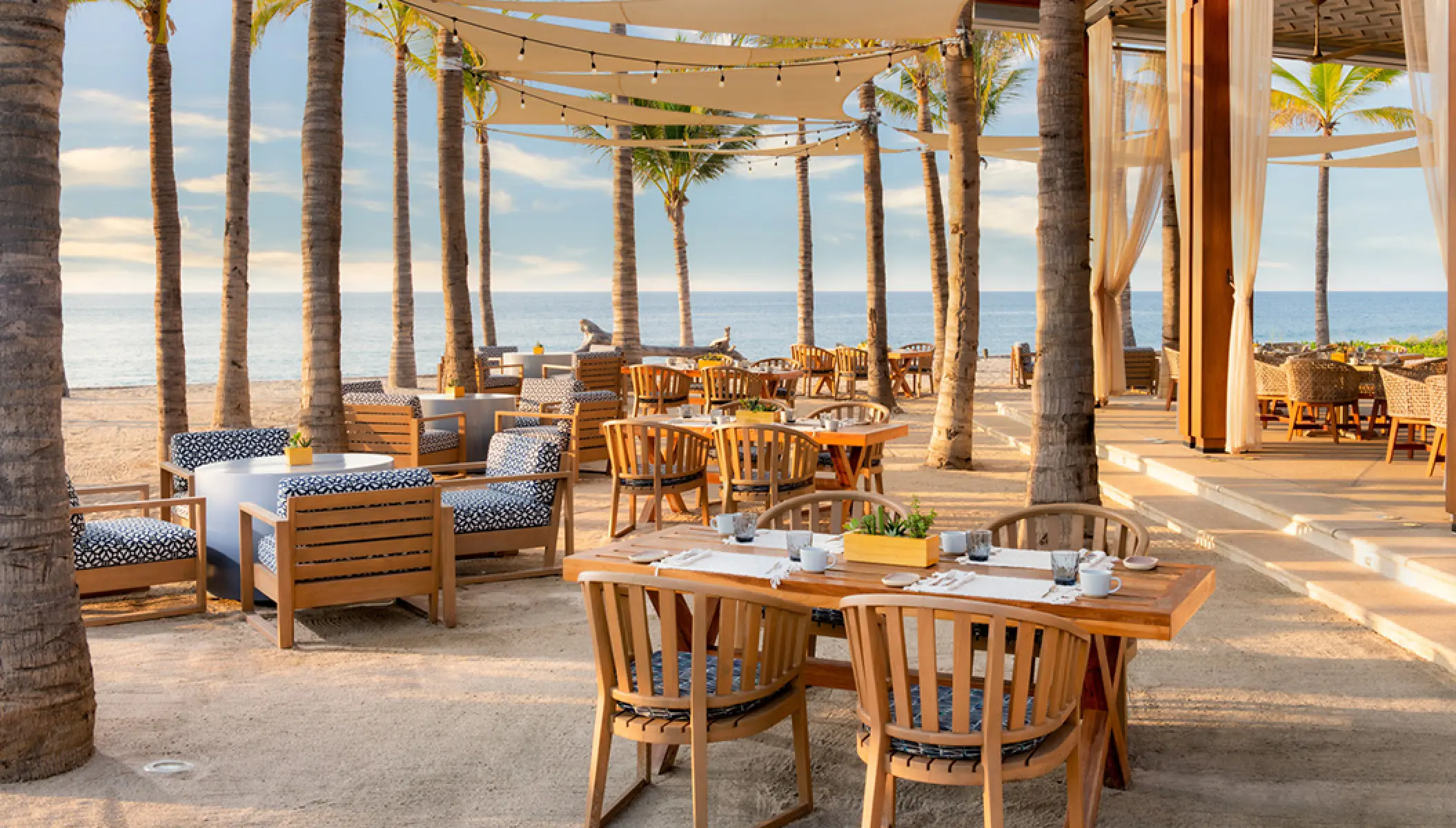 Beachfront dining area at Conrad Punta de Mita under palm trees, Puerto Vallarta