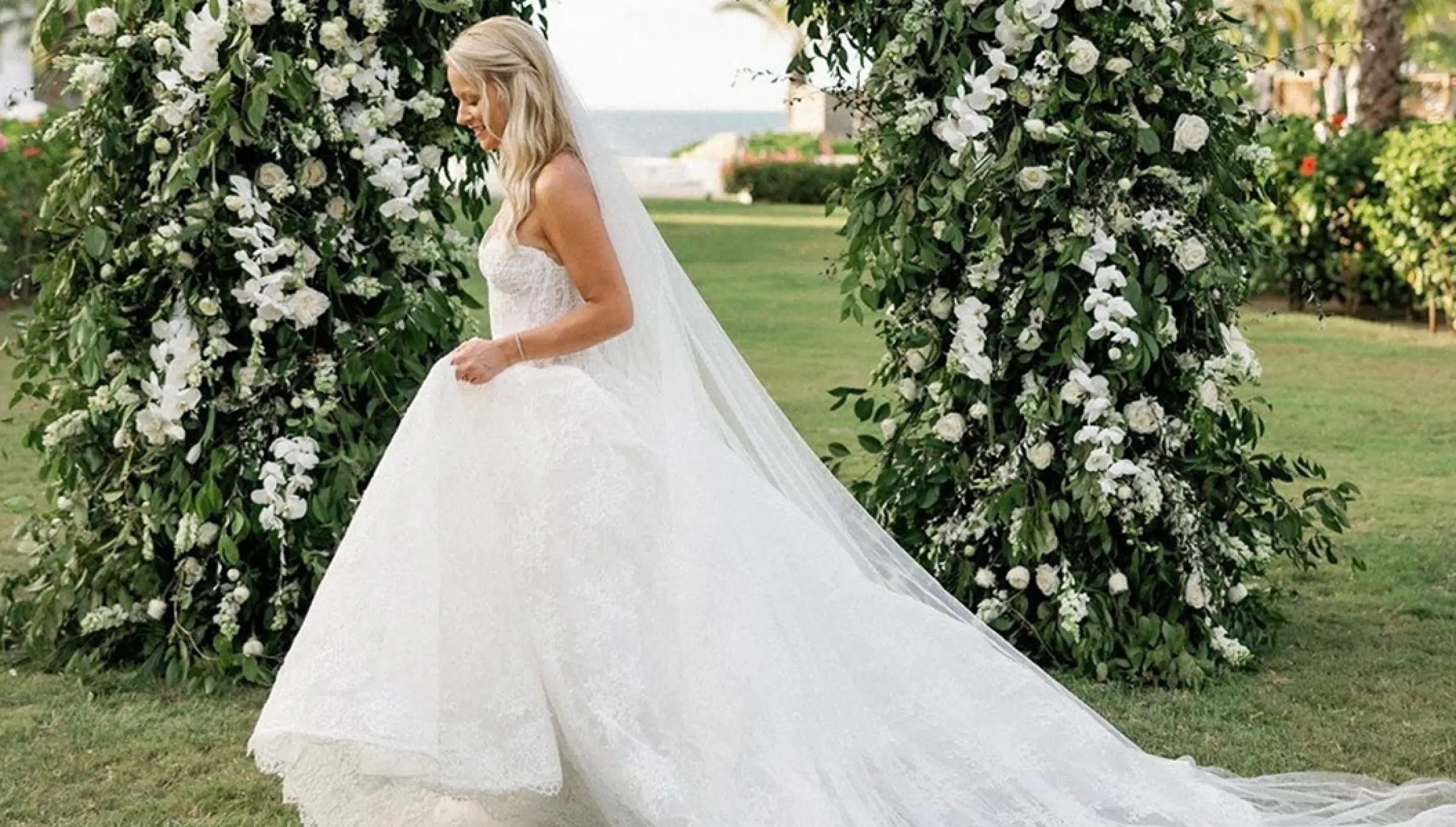 Bride walking past a floral wedding arch at Conrad Punta de Mita, Puerto Vallarta
