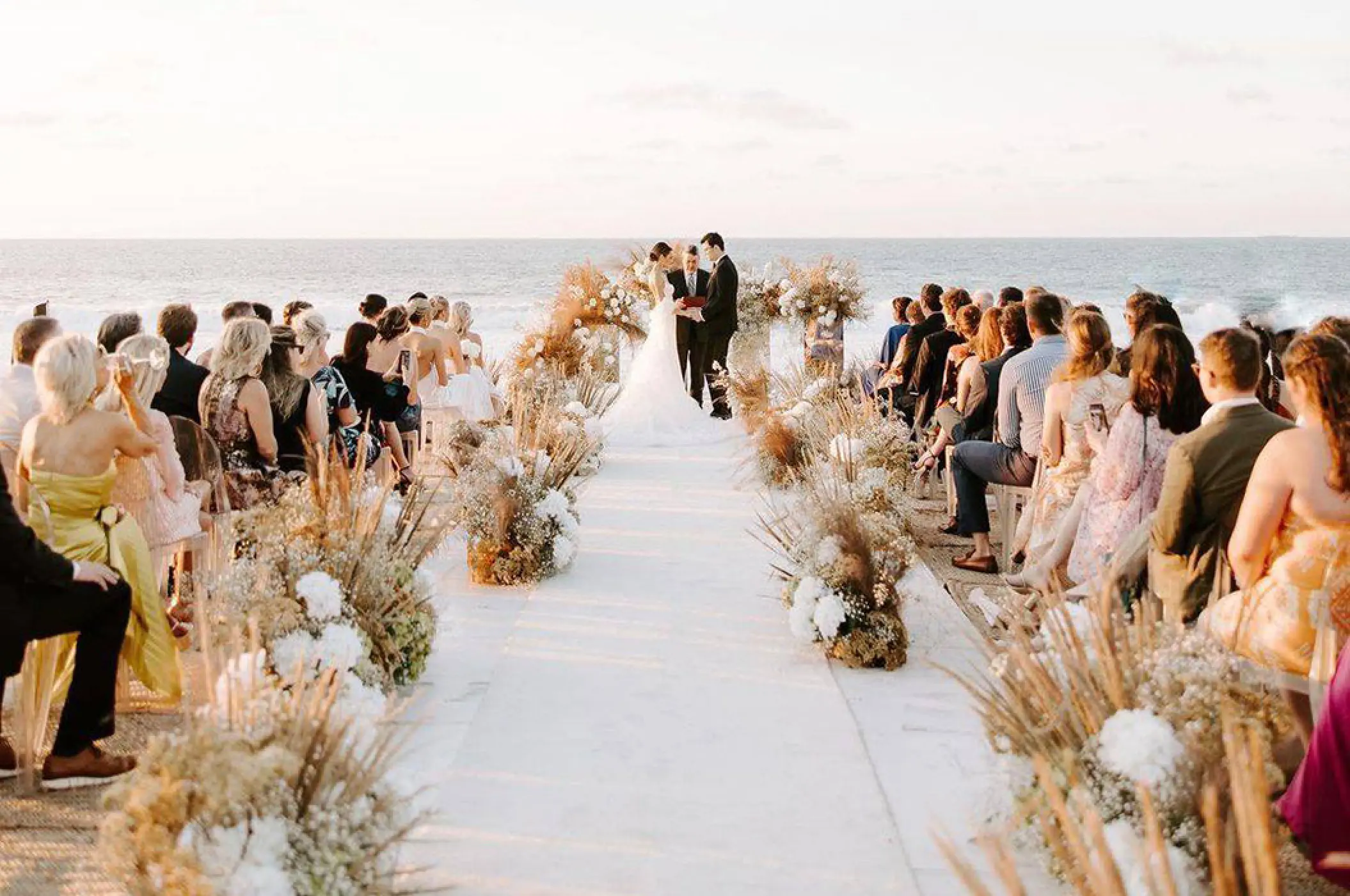 Beachfront wedding ceremony with white aisle and pampas grass at Conrad Punta de Mita, Puerto Vallarta