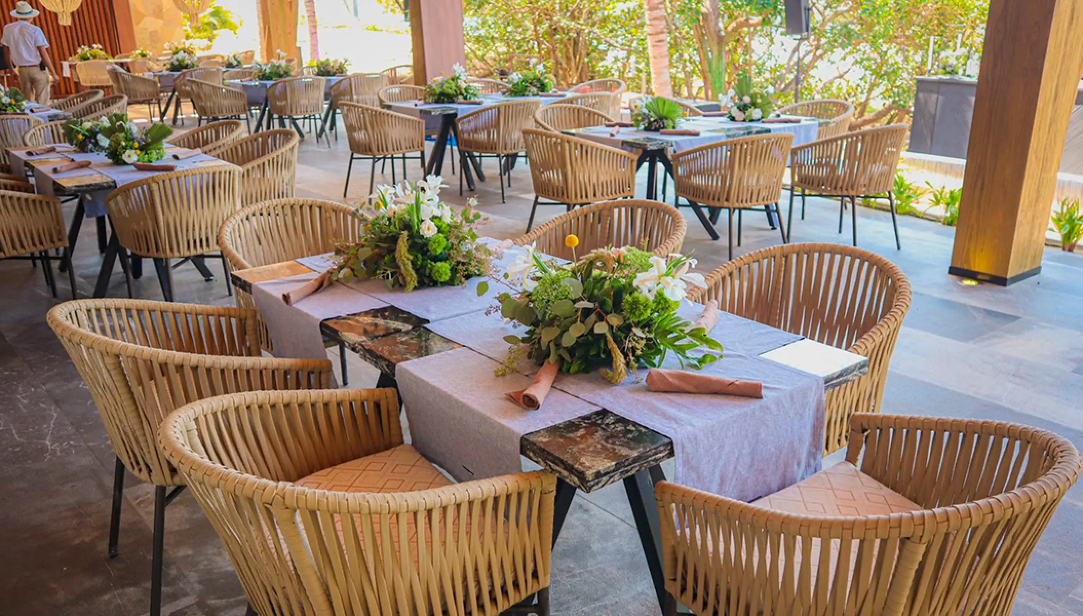 Wedding reception tables with floral centerpieces and woven chairs at Conrad Punta de Mita, Puerto Vallarta