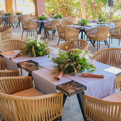 Wedding reception tables with floral centerpieces and woven chairs at Conrad Punta de Mita, Puerto Vallarta