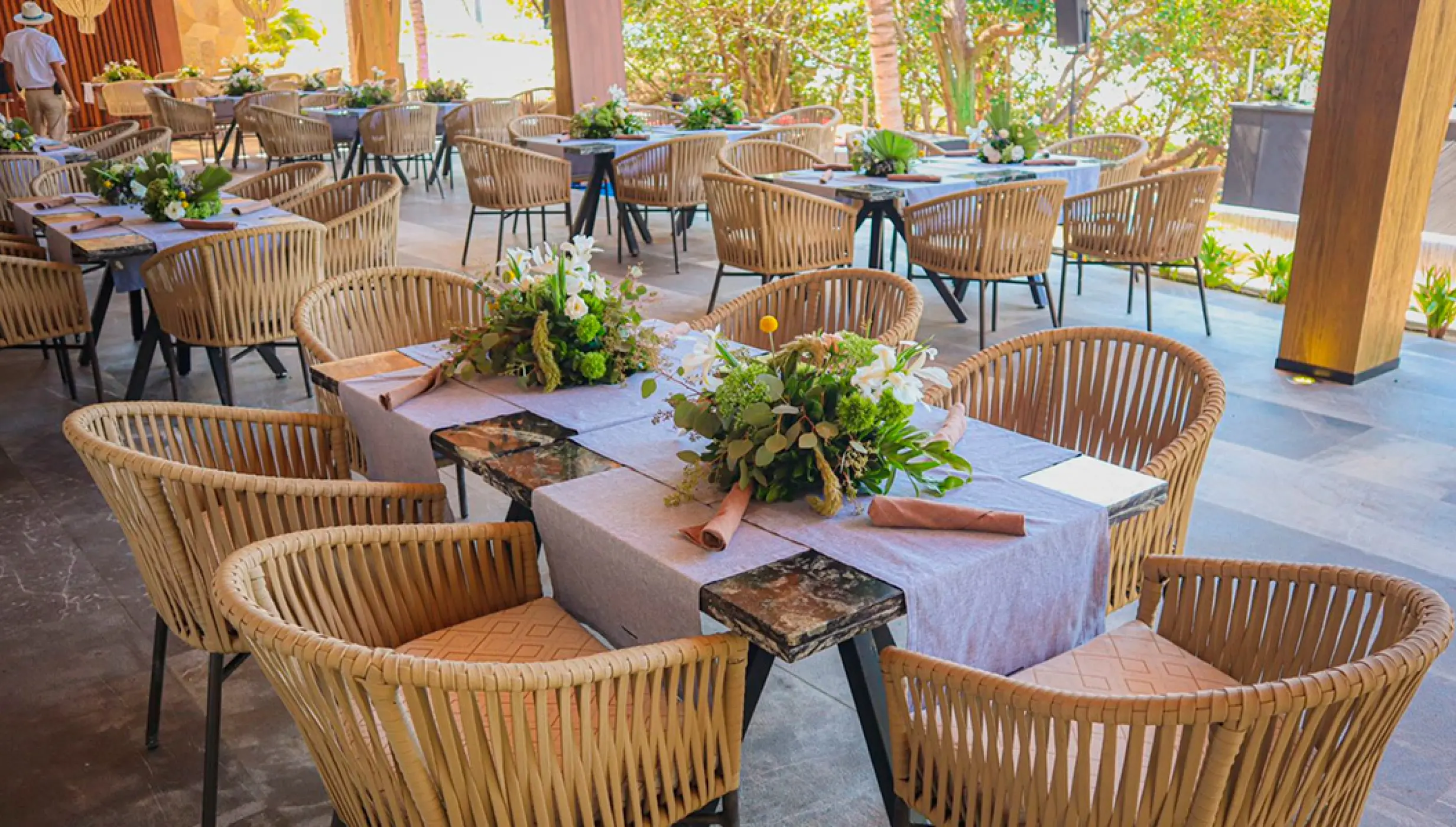 Wedding reception tables with floral centerpieces and woven chairs at Conrad Punta de Mita, Puerto Vallarta
