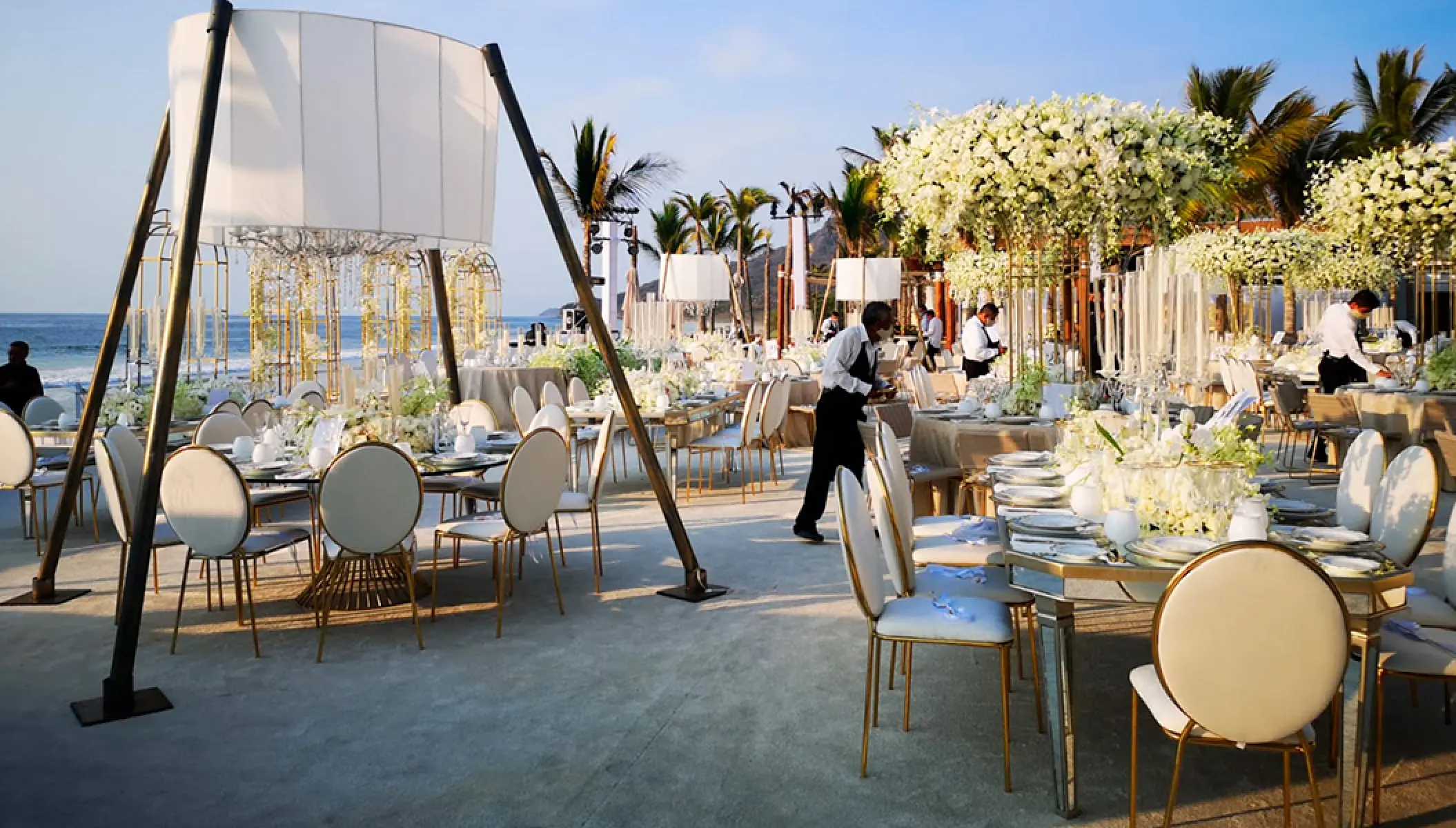 Outdoor wedding reception with white floral centerpieces and chandeliers at Conrad Punta de Mita, Puerto Vallarta