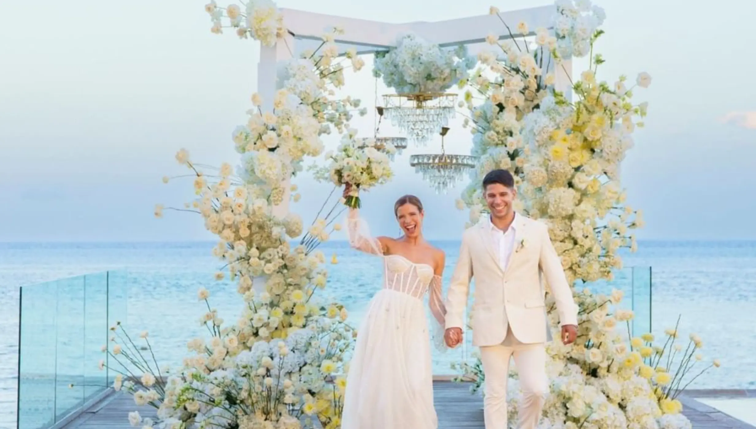 The bride and groom walking from a floral arch at Devossion by Live Aqua, Playa Del Carmen