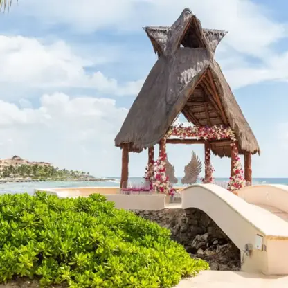 Thatched roof wedding gazebo with floral decor and ocean views at Dreams Aventuras, Riviera Maya