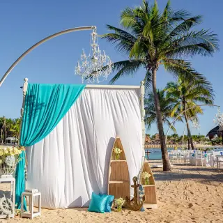Beachfront wedding ceremony setup with white and turquoise draping and chandeliers at Dreams Aventuras, Riviera Maya