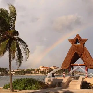 Thatched oceanfront wedding gazebo under a rainbow at Dreams Aventuras, Riviera Maya