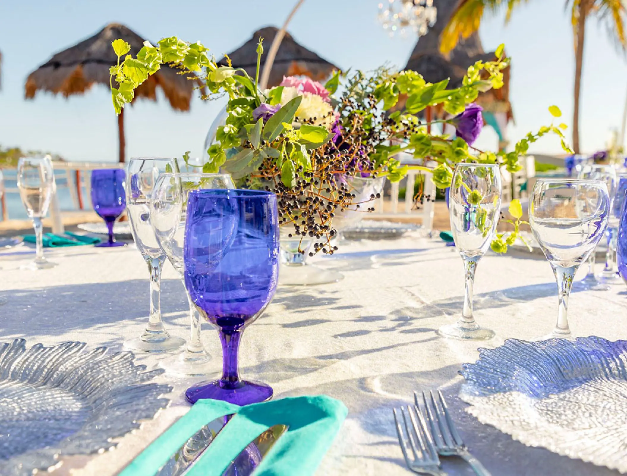 Outdoor wedding reception table with blue glassware and floral centerpiece at Dreams Aventuras, Riviera Maya