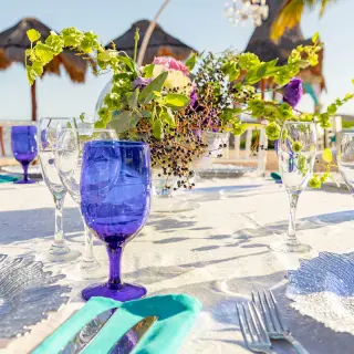 Outdoor wedding reception table with blue glassware and floral centerpiece at Dreams Aventuras, Riviera Maya