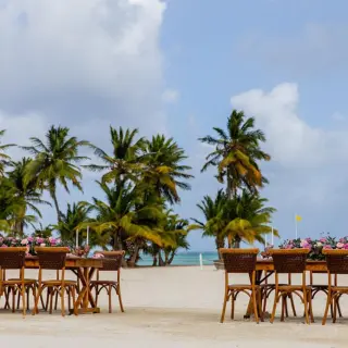 Beachfront wedding reception setup with wooden tables and palm trees at Dreams Cap Cana, Punta Cana