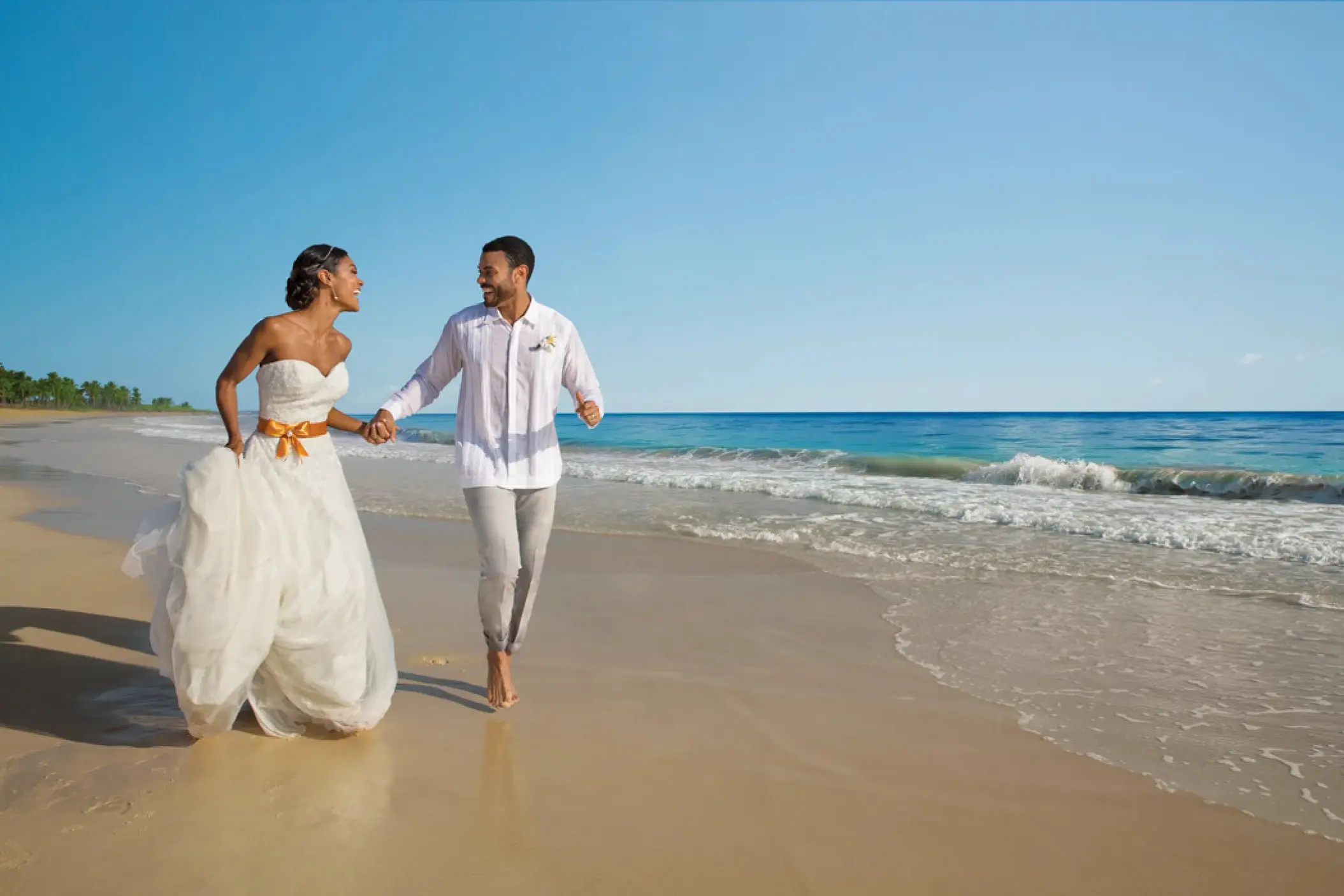Bride and groom running along the beach at Dreams Cap Cana, Punta Cana